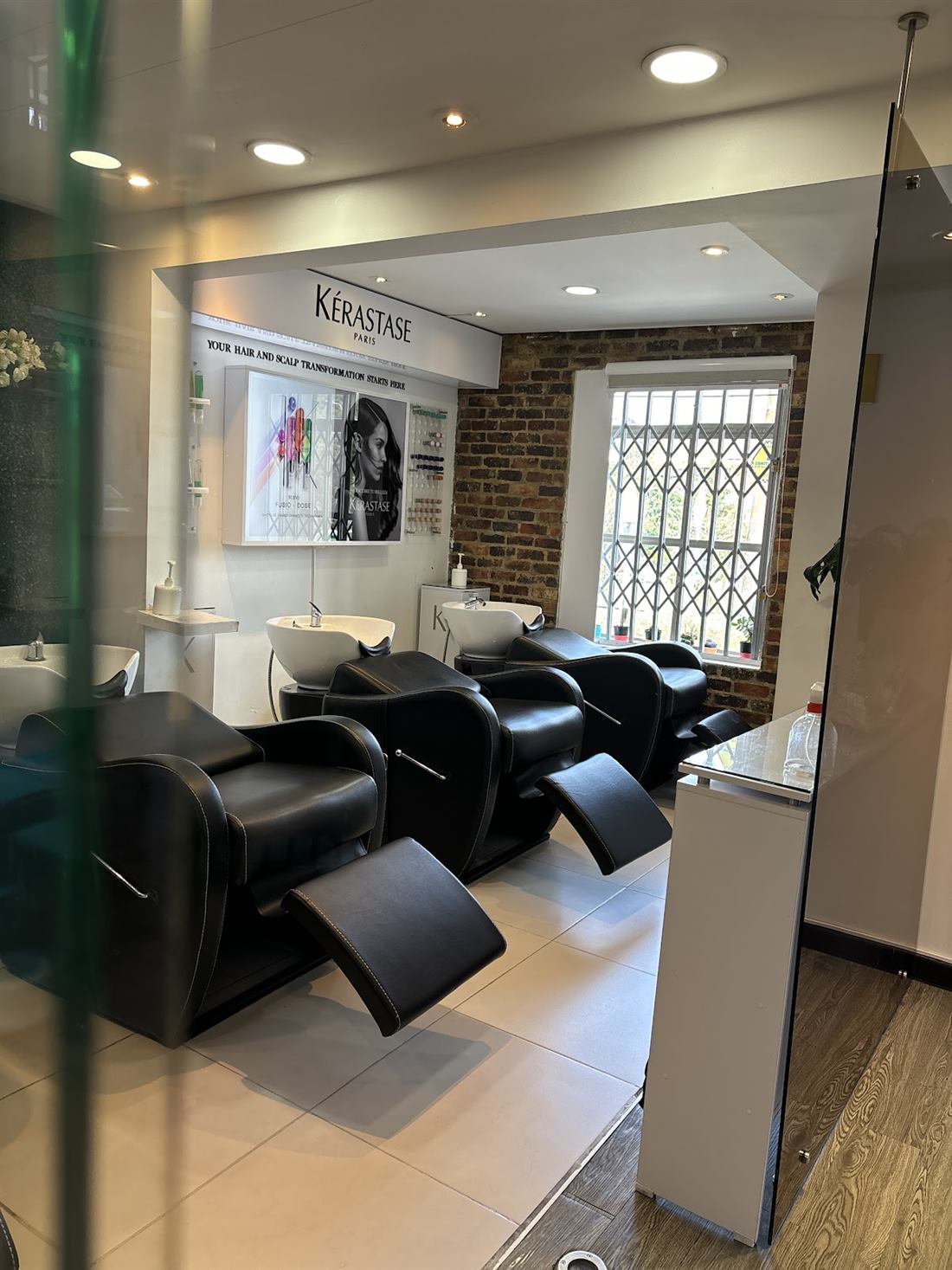 Zona de lavado con sillones negros reclinables y exhibidor Kérastase
